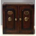 AN EARLY 20TH CENTURY OAK TABLE TOP COLLECTOR'S CHEST In the form of a safe, the two doors with