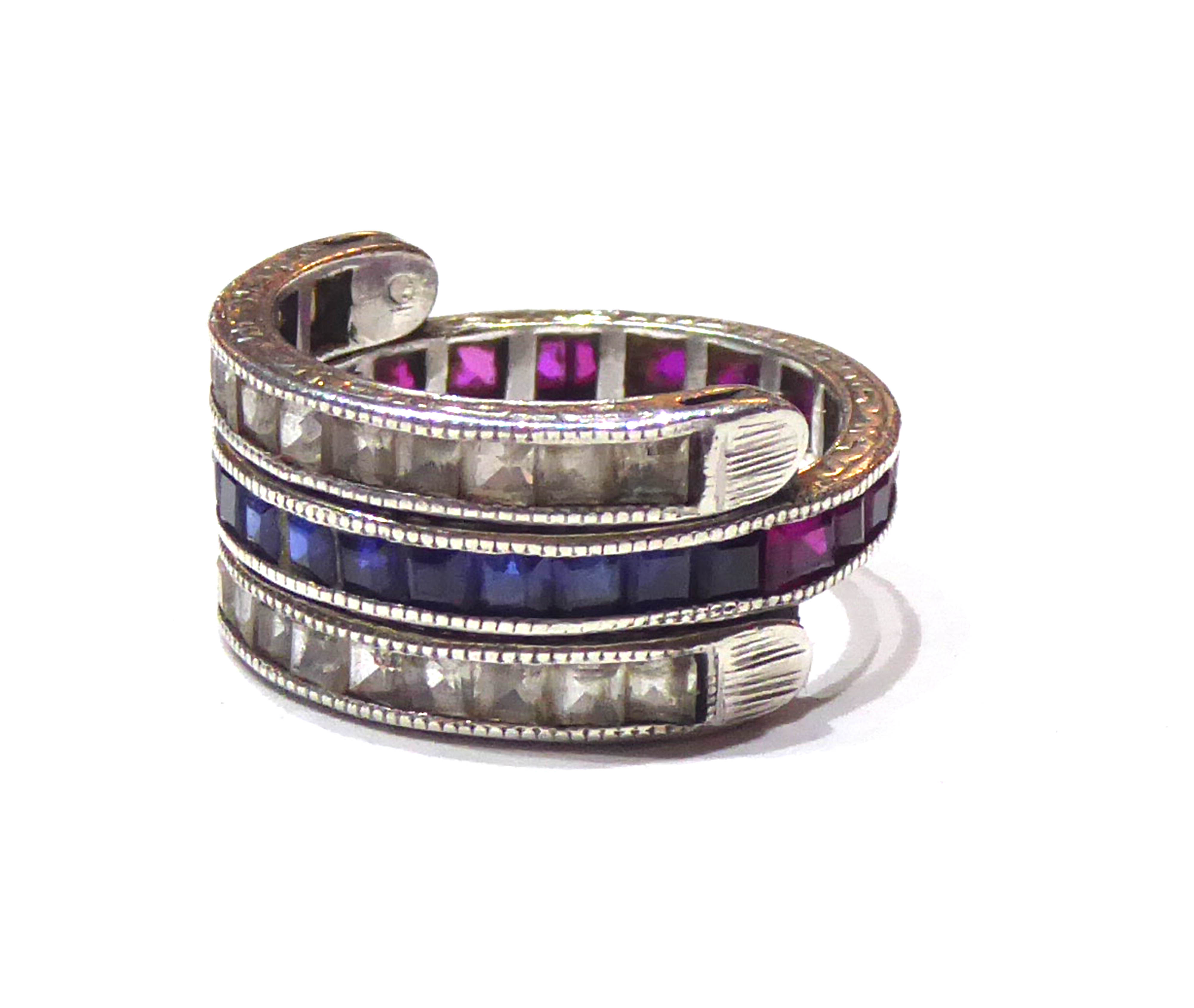 AN ART DECO WHITE METAL RUBY AND SAPPHIRE SWING OVER RING The row of baguette cut rubies