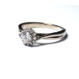 AN 18K WHITE GOLD AND DIAMOND HALO SET RING The round brilliant cut central stone 0.31ct (size L).