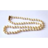 A VINTAGE YELLOW METAL AND PEARL NECKLACE The strand of uniform pearls with elongated yellow metal