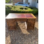 AN EARLY 20TH CENTURY OAK TWIN PEDESTAL DESK With red tooled leather surface above an arrangement of