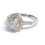 AN 18CT WHITE AND DIAMOND GOLD HALO RING The central claw set stone 1.2ct, on diamond shoulders (