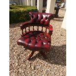 A RED BUTTON BACK LEATHER CAPTAIN'S CHAIR ON SWIVEL BASE.