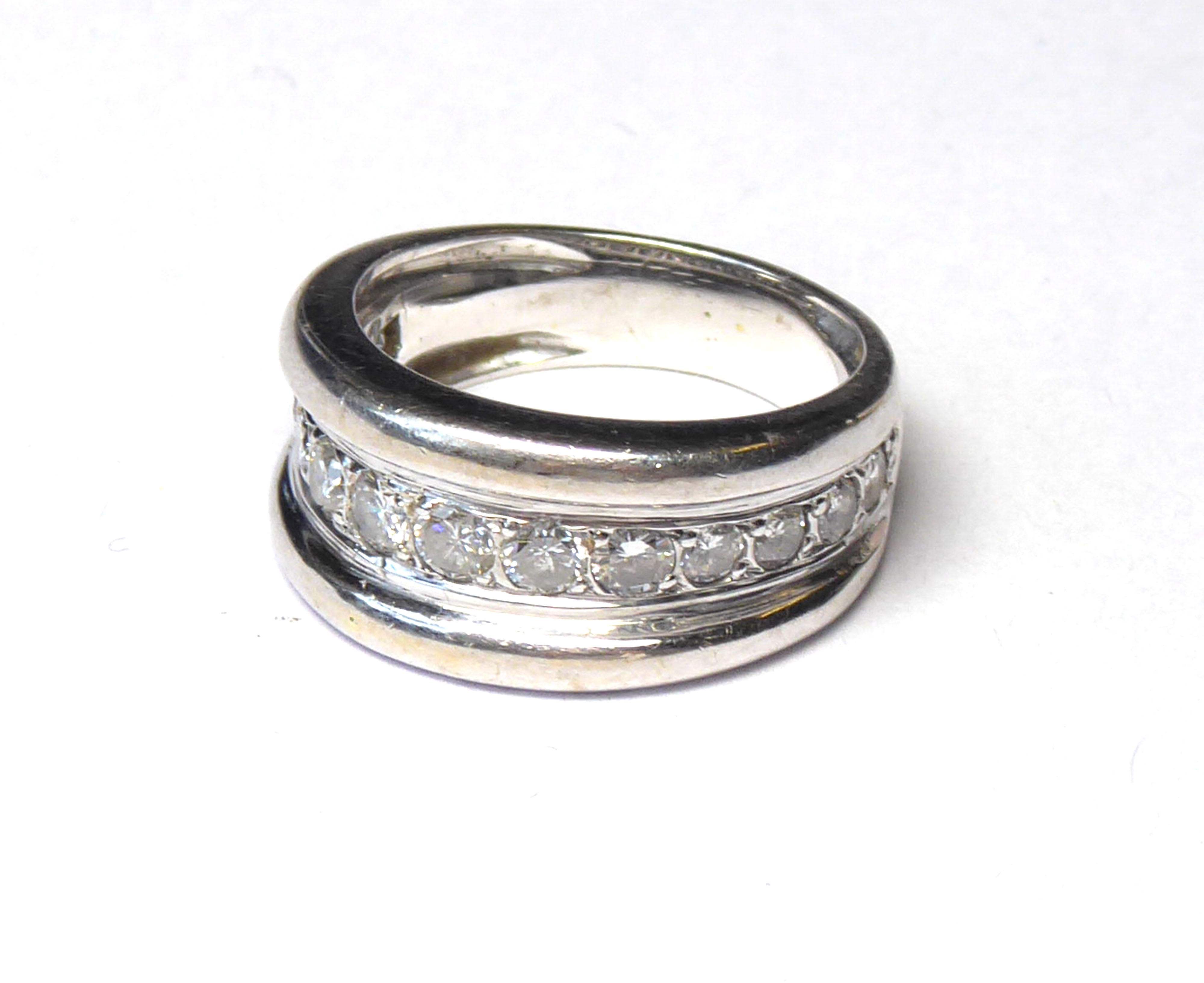 A WHITE METAL AND DIAMOND BAND RING The arrangement of graduating stones in a run over setting (size