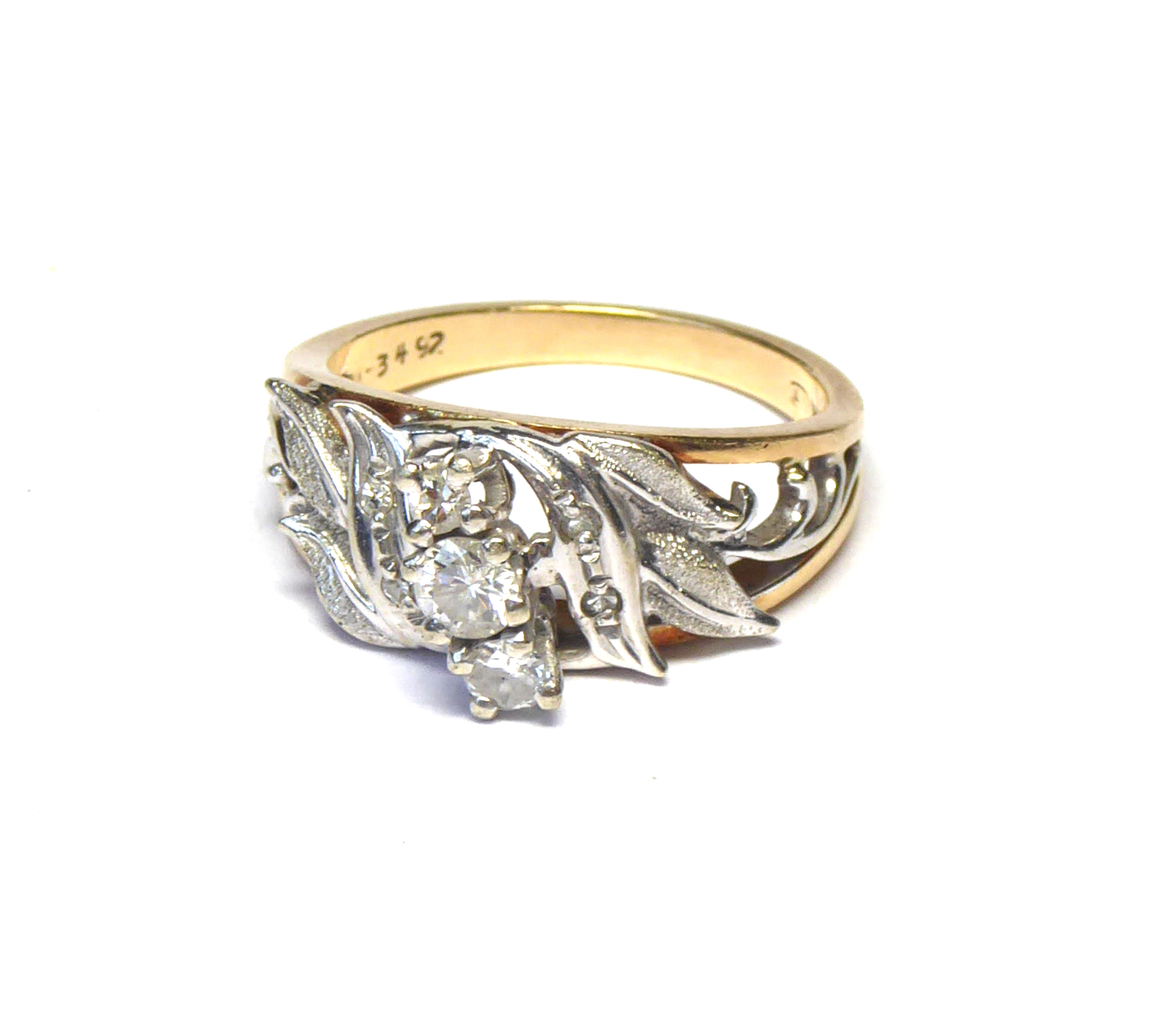 A 14K GOLD AND DIAMOND THREE STONE RING The graduated stones in a white gold pierced mount on yellow