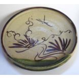 A JAPANESE ORIBE POTTERY PLATE Having a shallow rim and hand painted decoration. (approx 22cm)