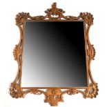 AN EARLY 20TH CENTURY MAHOGANY MIRROR Having pierced form frame carved with scrolls and shells.
