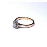 AN 18K GOLD AND DIAMOND HALO SET RING The round brilliant cut central stone 0.30ct (size M).