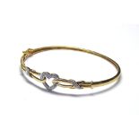 A 9CT GOLD AND DIAMOND BANGLE Heart form motif set with pavé diamonds on a rope twist mount. (approx