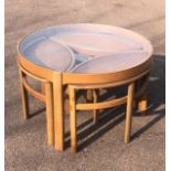 A NEST OF FIVE MID 20TH CENTURY TEAK TABLES The circular top with inset glazed top above four pull