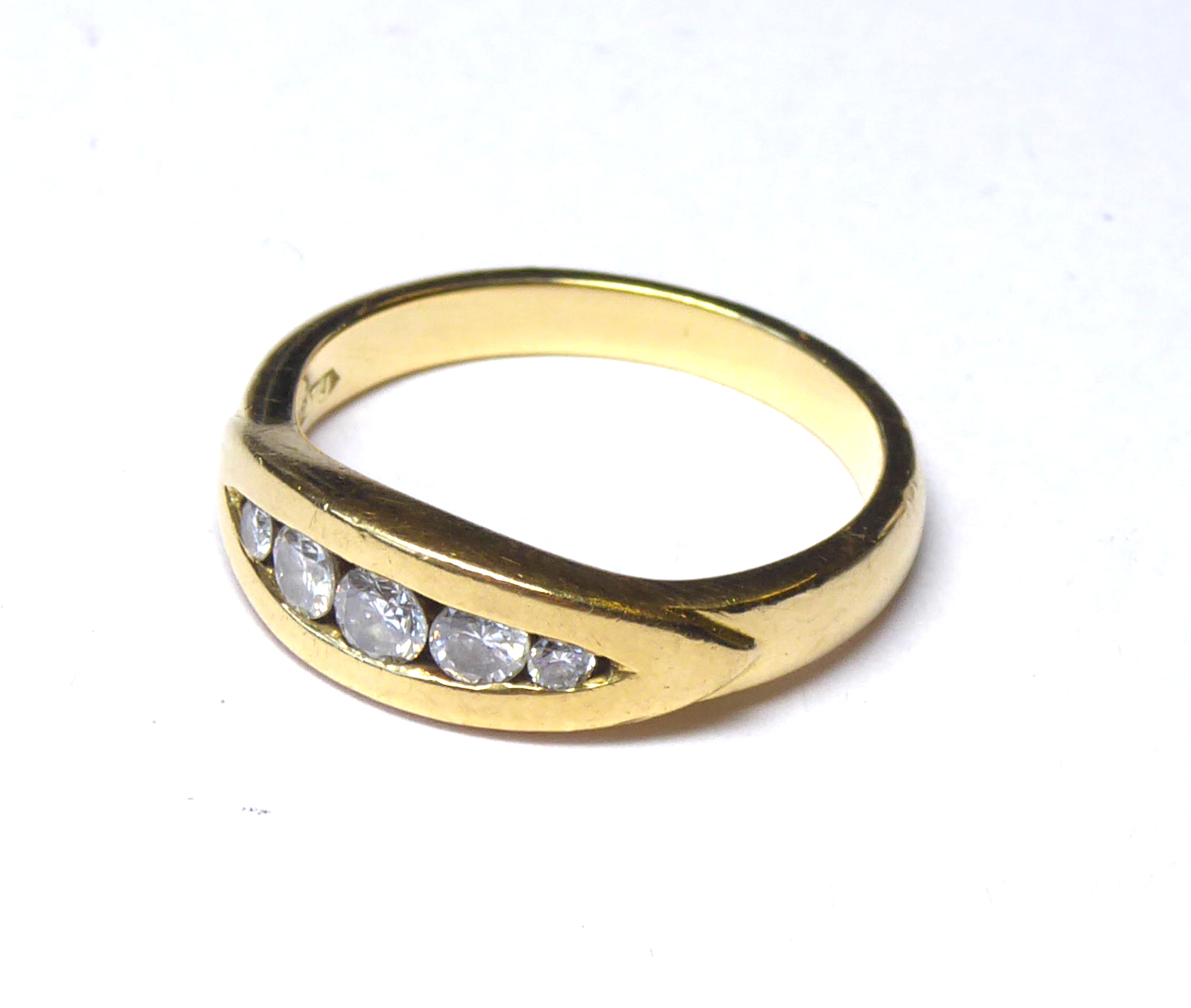 AN 18CT GOLD AND DIAMOMD FIVE STONE RING Graduating round cut stones in a rub over setting (size N).