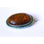 A LARGE OVAL AMBER BROOCH In white metal setting. (5.3cm)