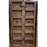 A PAIR OF ANTIQUE INDIAN HARDWOOD DESTRESSED PANELLED DOORS With strap iron work and nail head