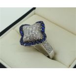 AN 18CT WHITE GOLD, DIAMOND AND SAPPHIRE CLUSTER RING The arrangement of diamonds edged with