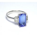 AN 18K WHITE GOLD RING SET WITH A 3.37 CT EMERALD CUT TANZANITE On diamond shoulders (size M).