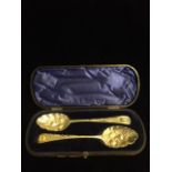A CASED PAIR OF GEORGIAN SILVER BERRY SPOONS Having gone engraved decoration and embossed fruit to