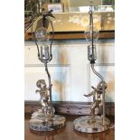 A PAIR OF EARLY 20TH CENTURY TABLE LAMPS Figured with silvered bronze prancing winged cherubs, on