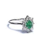 AN 18CT WHITE GOLD, EMERALD AND DIAMOND RING The oval cut emerald edged with round cut diamonds,