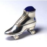 A STERLING SILVER NOVELTY ROLLER SKATE FORM PIN CUSHION Having a blue velvet cushion. (approx 4cm)