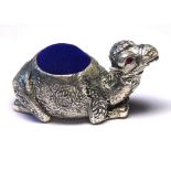 A SILVER PLATED NOVELTY RECUMBENT CAMEL FORM PIN CUSHION With blue velvet cushion. (approx 5.5cm x