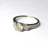 AN 18CT WHITE GOLD AND DIAMOND THREE STONE RING A central round cut diamond d, flanked by diamonds