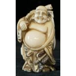 A 19th CENTURY JAPANESE MEIJI CARVED IVORY NETSUKE, a standing Buddha with red enamel engraving.