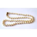 A VINTAGE YELLOW METAL AND PEARL NECKLACE The strand of uniform pearls with elongated yellow metal