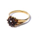 A VINTAGE 9CT GOLD AND GARNET RING The arrangement of round cut stones forming a daisy cluster (size