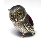 A STERLING SILVER NOVELTY OWL FORM PIN CUSHION Having glass set eyes and red velvet cushion.