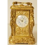 A GILT BRASS FIGURAL MINIATURE CARRIAGE CLOCK With Katydid supports and scrolled ornate case. (