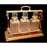 AN EDWARDIAN SILVER PLATED OAK AND CUT GLASS TANTALUS Rectangular form with hinged handle and