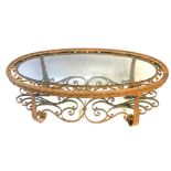 A 20TH CENTURY CONTINENTAL TWO TIER WROUGHT IRON GLASS TOP OVAL COFFEE TABLE Decorated with gilt
