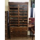 AN EARLY 20TH CENTURY OAK SHOPS HABERDASHERS CABINET With sixteen glazed short drawers above four