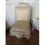 A LATE VICTORIAN NURSING CHAIR In a cream fabric upholstery, raised on turned legs with casters. (