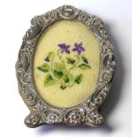 A VICTORIAN SILVER OVAL PHOTOGRAPH FRAME Having embossed floral decoration and easel frame. (