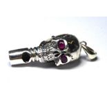 A SILVER NOVELTY SKULL FORM WHISTLE Having red glass set eyes. (approx 3.5cm)