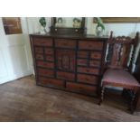 A 19TH CENTURY OAK BANK OF TWENTY-TWO DRAWERS The central fitted cupboard with carved panel door. (