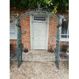 A STYLISH GREEN PATINATED WROUGHT IRON GARDEN ARCH Crested with a scroll work cartouche above facial