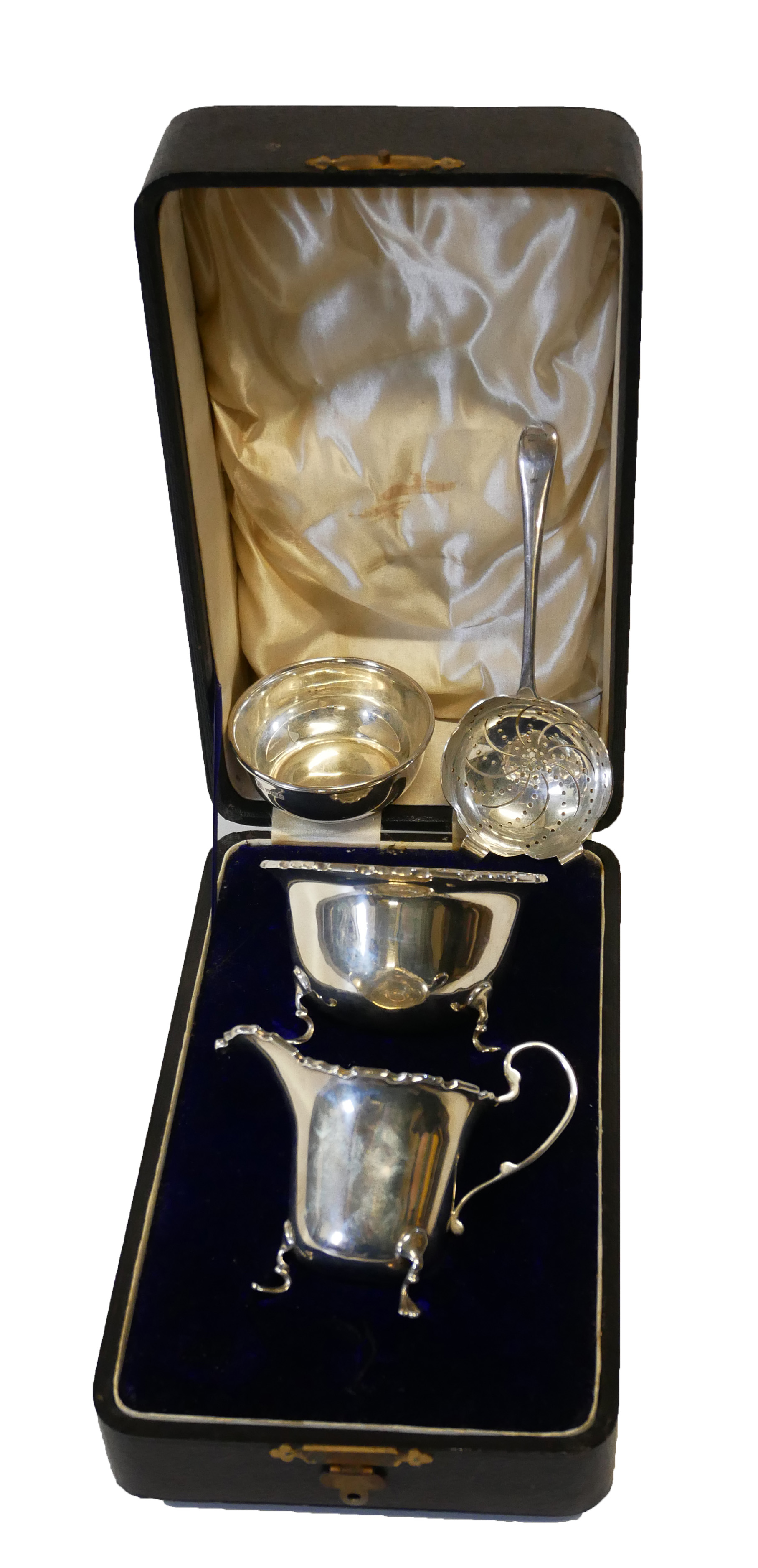 A HALLMARKED SILVER STRAINER ON STAND Along with a cased sugar bowl and cream jug.