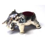 A SILVER NOVELTY ELEPHANT FORM PIN CUSHION Standing pose glass set eyes and red velvet cushion. (