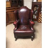 AN EARLY 20TH CENTURY GEORGIAN DESIGN WING ARMCHAIR Red leather upholstery, raised on cabriole legs.