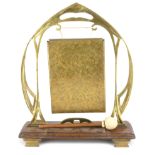 AN ART NOUVEAU BRASS AND OAK TABLE GONG Stylised frame with rectangular gong on oak stand with