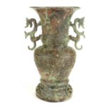 A CHINESE ARCHAIC FORM VASE Twin dragon handles with embossed decoration and Verdigris. (approx
