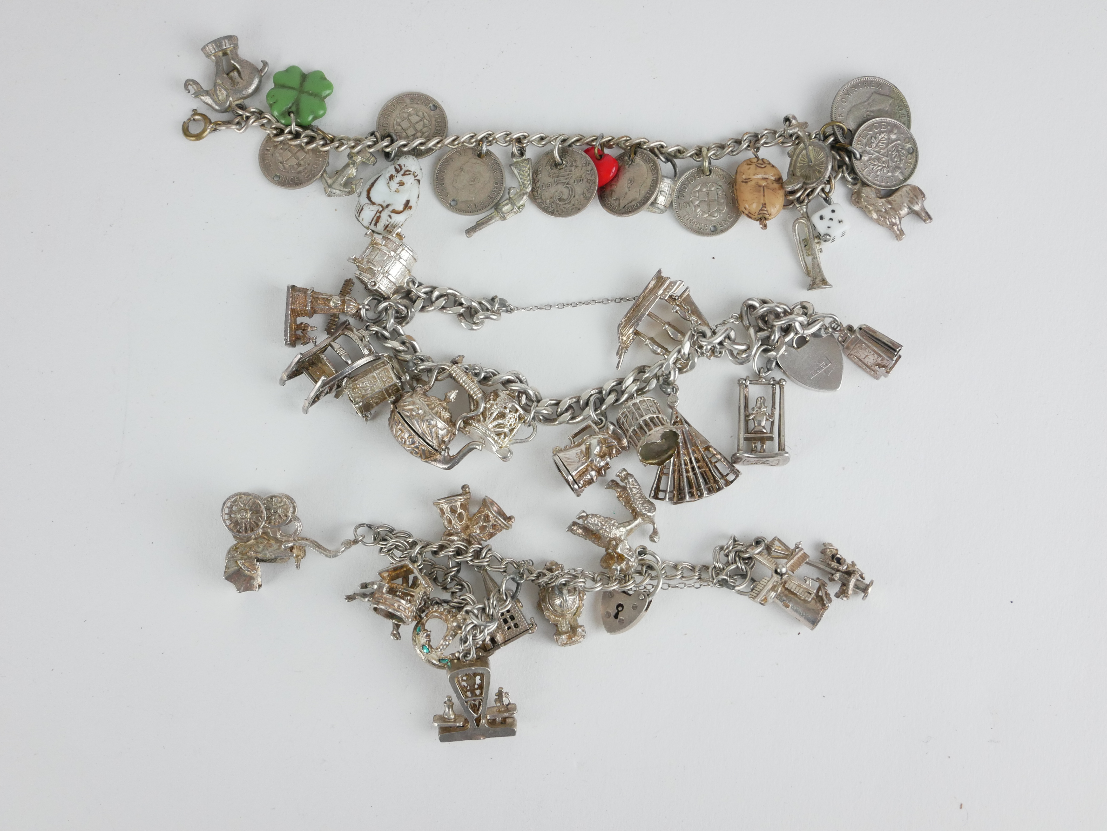 THREE VINTAGE SILVER CHARM BRACELETS Two bracelets having multiple novelty charms and one bracelet