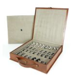 A CASED LEATHER BOUND AND METALLIC CHESS SET The chrome finish pieces set in a fitted brown case