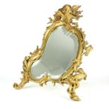 A 19TH CENTURY FRENCH GILT BRONZE CARTOUCHE EASEL BACK MIRROR The shaped bevelled mirror, within