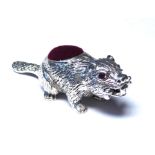 A NOVELTY STERLING SILVER BEAVER PIN CUSHION Standing pose with ruby set eyes and red cushion. (