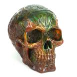 A FAUX AMBER HUMAN CARVED SKULL With all over relief decoration. (13cm)