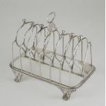 A GEORGE III SILVER TOASTRACK Having an oval form carry handle, ball finials, gadrooned border to
