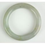 A CHINESE CARVEDN LIGHT GREEN/GREY JADE BANGLE Plain spherical design. (approx 8cm)